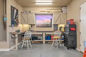 Office space with concrete flooring, a workshop area, and baseboards