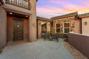 Doorway to property with a patio area, stone siding, stucco siding, and a tiled roof