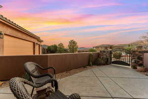 Patio terrace at dusk featuring a garage, a gate, and fence