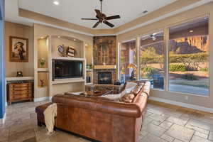 Living room featuring baseboards, visible vents, stone tile flooring, and a stone fireplace