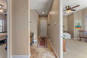 Hallway with attic access, recessed lighting, stone tile flooring, and baseboards