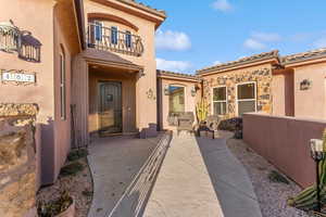 View of exterior entry featuring a patio, a tiled roof, a balcony, and stucco siding