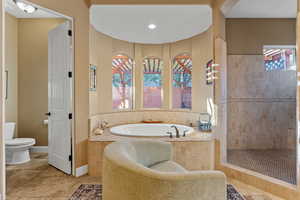 Full bathroom featuring walk in shower, a garden tub, toilet, and baseboards