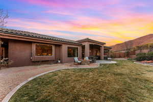 Back of property at dusk featuring a patio, a mountain view, a fire pit, fence, and a yard