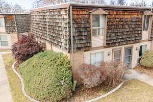 View of side of home with mansard roof and brick siding