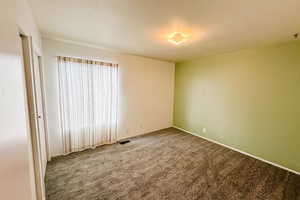 Carpeted empty room featuring baseboards and visible vents