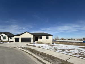 View of front of property with driveway, an attached garage, and stucco siding