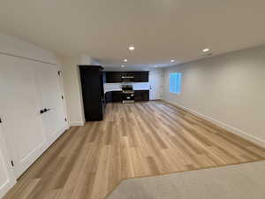 Unfurnished living room with light wood-style flooring, baseboards, and recessed lighting