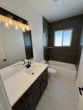 Bathroom with a chandelier, tile patterned flooring, toilet, vanity, and shower / washtub combination