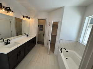 Full bathroom featuring a stall shower, a textured ceiling, a walk in closet, and a sink