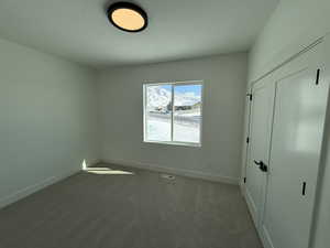 Unfurnished bedroom with a textured ceiling, visible vents, baseboards, a closet, and carpet