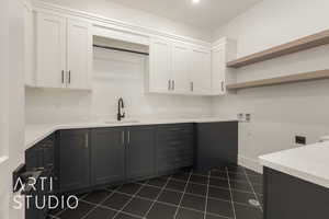 Kitchen with white cabinets, light countertops, dark tile patterned floors, open shelves, and a sink