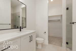 Bathroom with a stall shower, baseboards, toilet, a spacious closet, and vanity