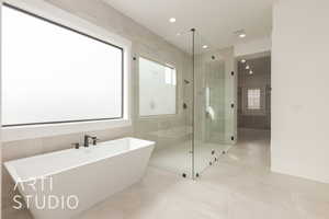 Bathroom featuring a freestanding tub, recessed lighting, tile walls, and a stall shower