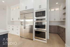 Kitchen with built in appliances, open shelves, glass insert cabinets, and white cabinets