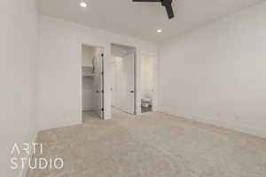 Unfurnished bedroom featuring light carpet, a spacious closet, baseboards, and recessed lighting