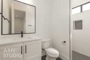 Bathroom featuring toilet, a walk in shower, and vanity