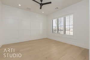 Spare room featuring light wood finished floors, visible vents, and a decorative wall