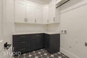 Interior space with baseboards, hookup for a washing machine, cabinet space, and electric dryer hookup