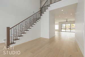 Stairs featuring recessed lighting, a towering ceiling, baseboards, and wood finished floors