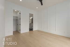 Unfurnished bedroom with light wood-style floors, a spacious closet, a decorative wall, and recessed lighting