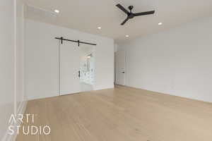 Unfurnished bedroom featuring a barn door, recessed lighting, visible vents, baseboards, and light wood-style floors