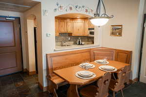 Kitchen featuring arched walkways, light countertops, tasteful backsplash, stainless steel microwave, and decorative light fixtures