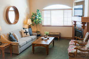 Living area with a healthy amount of sunlight, a fireplace, baseboards, and dark colored carpet