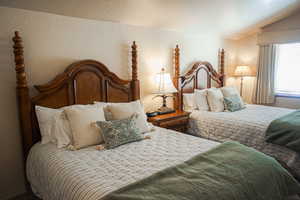 Bedroom featuring vaulted ceiling, a textured wall, and a textured ceiling