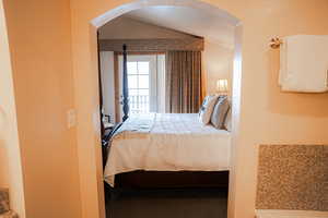 Bedroom with access to exterior, arched walkways, and vaulted ceiling