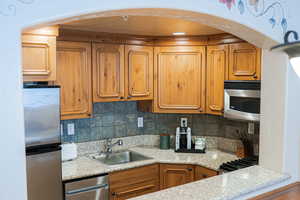 Kitchen featuring stainless steel appliances, tasteful backsplash, a sink, and brown cabinets