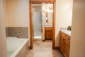 Full bath featuring a stall shower, a garden tub, vanity, and tile patterned floors