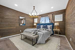 Bedroom featuring wooden walls, LVP Flooring, and an inviting chandelier