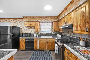 Kitchen featuring LVP flooring, under cabinet range hood, light countertops, and black appliances