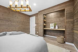 Bedroom featuring wooden walls, LVP Flooring, and an inviting chandelier.  The closet can easily be converted back