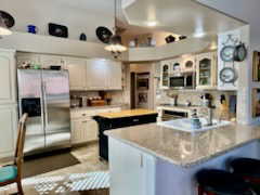 Kitchen with white cabinetry, kitchen peninsula, stainless steel appliances, a center island, and pendant lighting