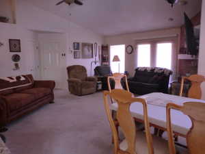 Living room featuring vaulted ceiling, light colored carpet, and ceiling fan