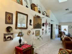 Corridor with light carpet and lofted ceiling with skylight