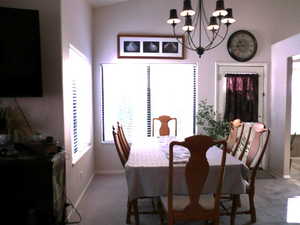 Dining space with a notable chandelier and light carpet