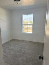 Empty room with visible vents, a textured ceiling, dark carpet, and a mountain view