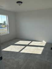 Spare room with dark carpet, visible vents, and baseboards