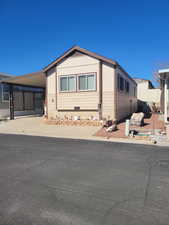 View of front of home featuring driveway, an attached carport, and fence