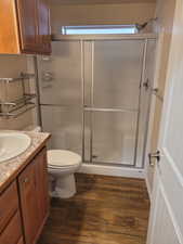 Full bath with toilet, a stall shower, wood finished floors, and vanity