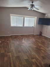 Unfurnished room featuring lofted ceiling, ceiling fan, dark wood-style flooring, and baseboards