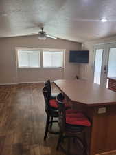 Kitchen featuring a textured ceiling, vaulted ceiling, dark wood-type flooring, and a center island