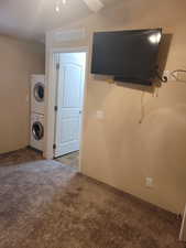 Laundry room with carpet, laundry area, stacked washer and dryer, and visible vents