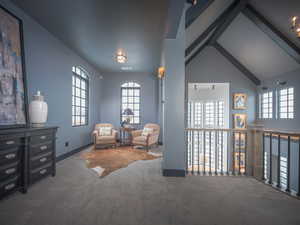 Sitting room with lofted ceiling with beams, carpet flooring, and baseboards