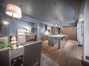 Dining space with a textured ceiling, arched walkways, and wood finished floors