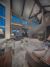 Living area with high vaulted ceiling, stairway, a chandelier, and beamed ceiling