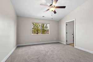 Spare room with ceiling fan, lofted ceiling, light carpet, visible vents, and baseboards